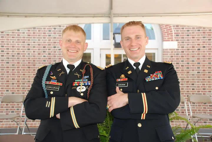 The Corcoran brothers in dress uniform smile for the camera as they stand outside a brick building.