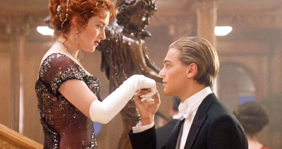 kate winslet and leonardo dicaprio in a scene from the film titanic, with dicaprio holding winslet's hand on a set of stairs, both of them in fancy attire