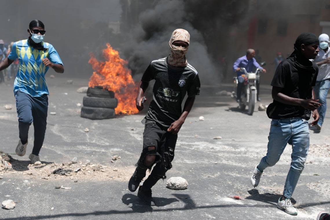 Protesters run for cover from tear gas fired by police during a protest against insecurity in Port-au-Prince, Haiti, Monday, Aug. 7, 2023.