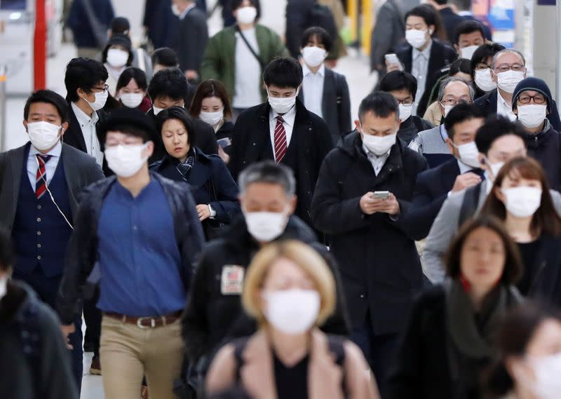 Passengers wearing protective face masks, following an outbreak of the coronavirus disease, walk to work the day before a state of emergency is expected to be imposed at a station in Tokyo