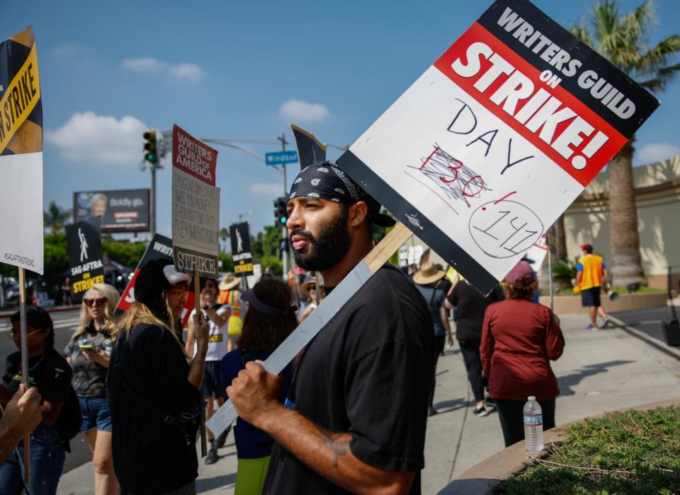 A picketer carries a sign outside a studio.