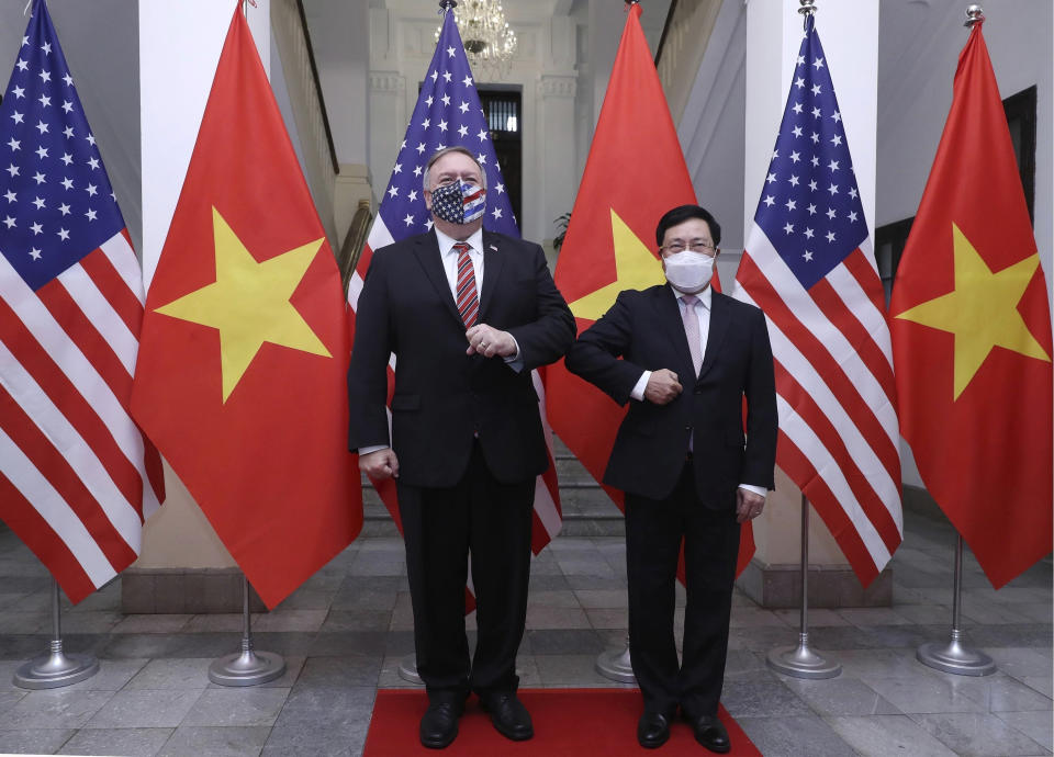 U.S. Secretary of State Mike Pompeo, left, and Vietnamese Foreign Minister Pham Binh Minh gesture with their elbows while posing for a photo before a meeting in Hanoi, Vietnam, Friday, Oct. 30, 2020. Pompeo is wrapping up an anti-China tour of Asia in Vietnam as the fierce American presidential election race enters its final stretch. (Bui Lam Khanh/VNA via AP)