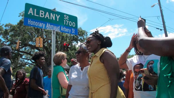 PHOTO: Wanda Cooper-Jones poses for photos with supporters beneath a new street sign honoring her son, Ahmaud Arbery, that was unveiled, Aug. 9, 2022, in Brunswick, Ga.  (Russ Bynum/AP)