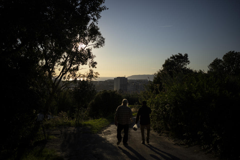 Residents Joel Schaegis, left, and Yaizid Bendaif, walk through the Worker's Gardens in Marseille, southern France, Tuesday, Oct. 26, 2021. Urban gardens are sprouting hope in drug- and violence-plagued neighborhoods of Marseille. From publicly funded city-wide initiatives to residents taking it upon themselves to start cultivating the land around them, urban farming is changing the landscape and creating a space for community. (AP Photo/Daniel Cole)