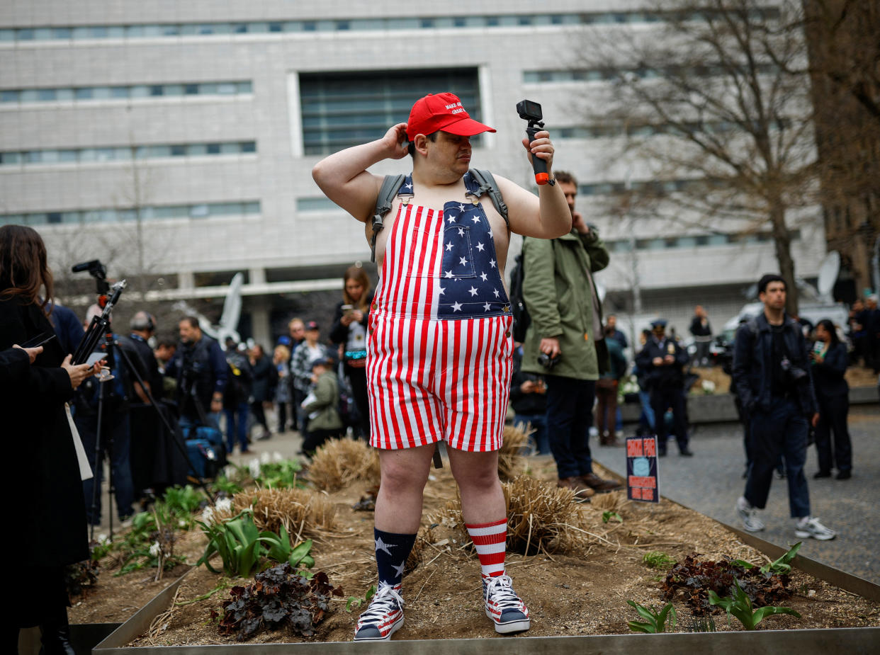 An anti-Trump demonstrator, wearing American flag overalls and holding a camera, outside the Manhattan Criminal Courthouse on Tuesday.
