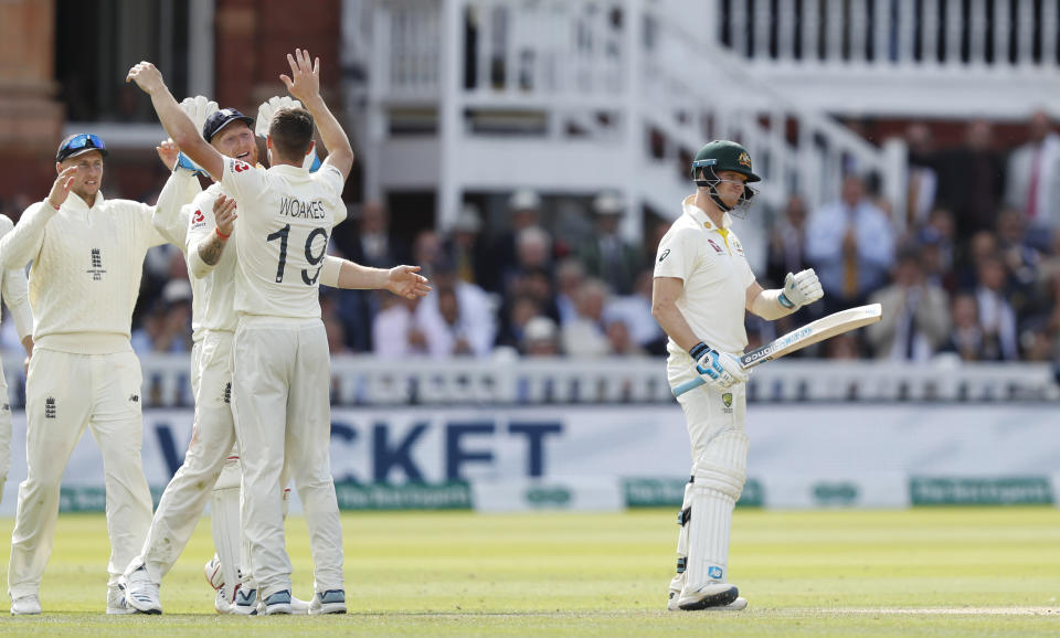 Australia's Steve Smith, right, looks round as England's Chris Woakes (19), celebrates with teammates after taking his wicket lbw during play on day four of the 2nd Ashes Test cricket match between England and Australia at Lord's cricket ground in London, Saturday, Aug. 17, 2019. (AP Photo/Alastair Grant)
