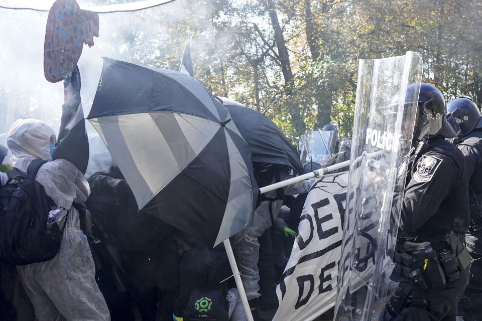 Protesters drive into a police line as gas floats in the air during a demonstration in opposition to a new police training center, Monday, Nov. 13, 2023, in Atlanta. (AP Photo/Mike Stewart)