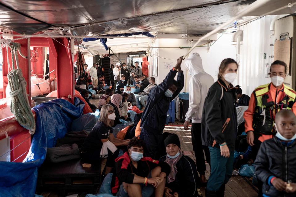 Migranten sitzen und stehen an Bord der Ocean Viking, bevor sie von Bord gehen.