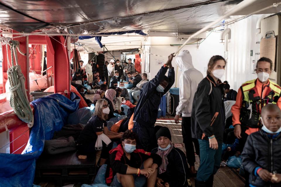 Migrants sit and stand on board the Ocean Viking prior to disembarking.