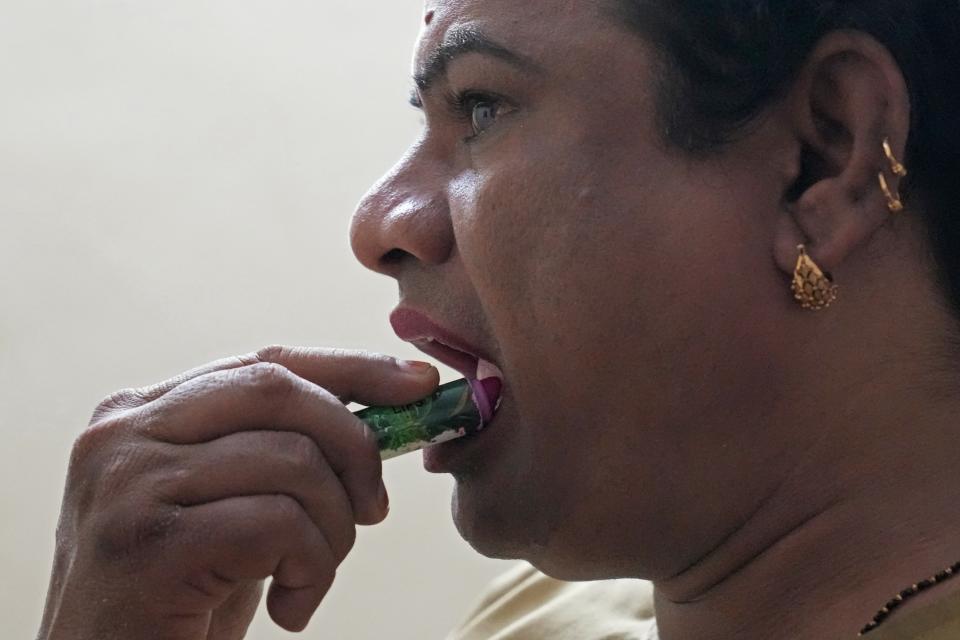 Preethi, a 38-year-old transgender woman who uses only her first name, applies lipstick as she gets ready at home before ferrying passengers in her electric auto rickshaw in Bengaluru, India, Wednesday, July 12, 2023. Preethi said she wants to see more people take up electric vehicles, particularly other transgender women. (AP Photo/Aijaz Rahi)