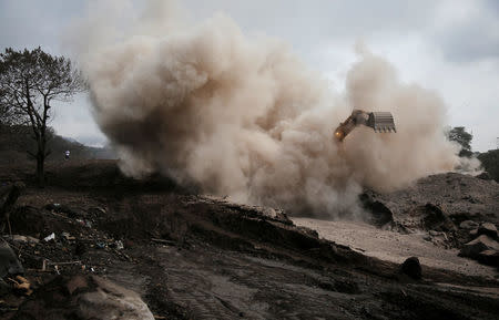 An excavator removes ash from an area affected by the eruption of Fuego volcano in San Miguel Los Lotes in Escuintla, Guatemala June 13, 2018. REUTERS/Luis Echeverria