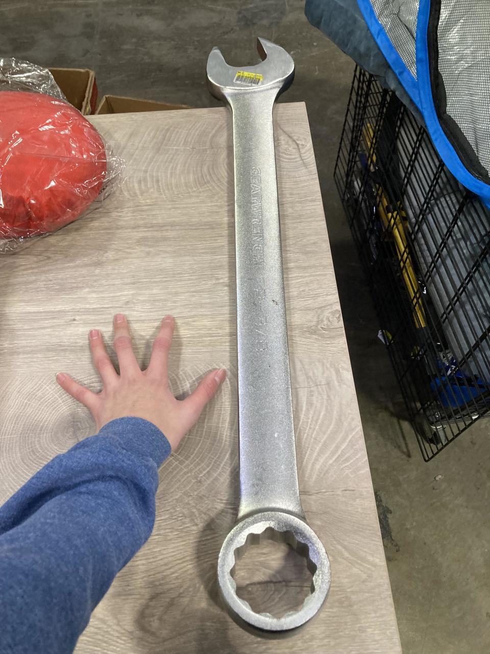 A giant wrench about twice as long as a person's arm next to it