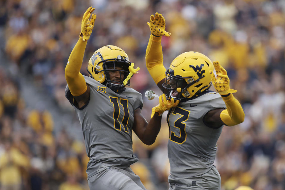 West Virginia's Beanie Bishop (11) celebrates an interception with Tomiwa Durojaiye (3) during the first half of an NCAA football game against Duquesne, Saturday, Sept. 9, 2023, in Morgantown, W.Va. (AP Photo/Chris Jackson)