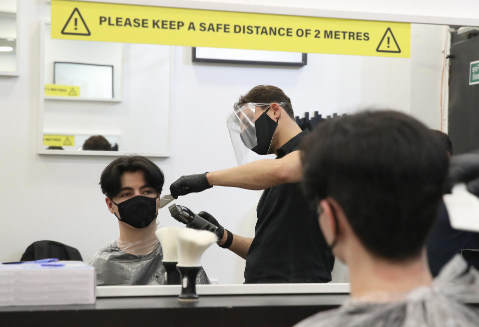 Barber Tony Mann with customer Sean Munro in the chair at Tony Mann's Barber Shop in Giffnock, Glasgow which opened at midnight as lockdown restrictions are relaxed. (Photo by Andrew Milligan/PA Images via Getty Images)