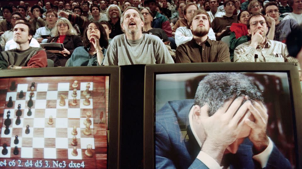 Chess enthusiasts watch world chess champion Garry Kasparov on a television monitor as he holds his head in his hands at the start of the sixth and final match May 11, 1997 against IBM's Deep Blue computer in New York. Kasparov lost this match in just 19 moves giving overall victory to Deep Blue with a score of 2.5-3.5. - Stan Honda/AFP/Getty Images
