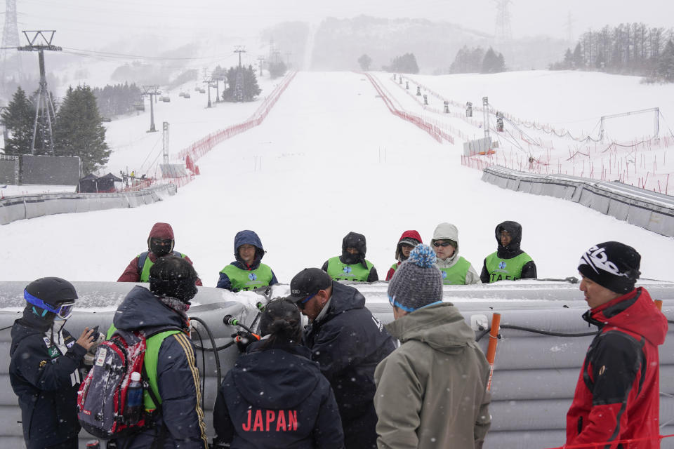 Event staff officials discuss the tear down of the venue facility after it was announced that the men's slalom race has been cancelled due to weather conditions during the 2020 Audi FIS Alpine Ski World Cup at Naeba Ski Resort in Yuzawa, Niigata prefecture, northern Japan, Sunday, Feb. 23, 2020. (AP Photo/Christopher Jue)