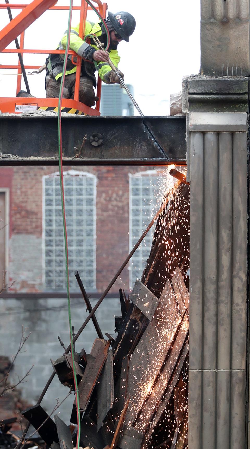 A demolition worker cuts a metal beam as part of the demolition of the buildings at 14 Lincoln Way E and 20 Lincoln Way E in Massillon on Sunday.