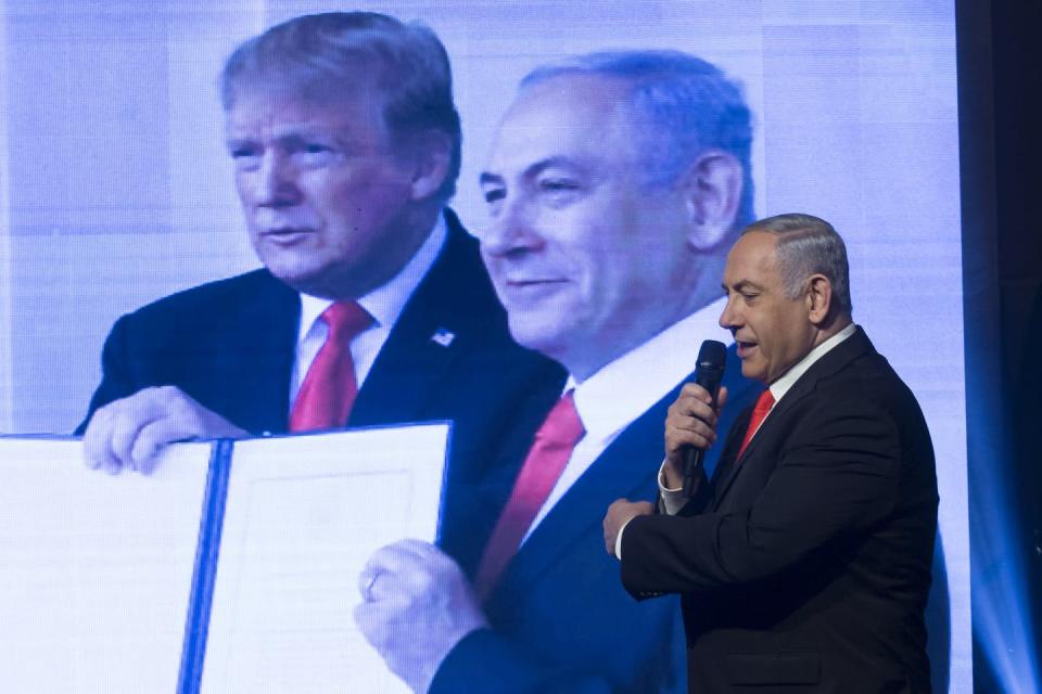 Benjamin Netanyahu stands in front of a large photo showing him and U.S. President Donald Trump.