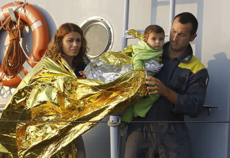 An Italian coast guard officer helps Syrian refugees from Kobani in the port of Kos following a rescue mission off the Greek island of Kos August 10, 2015. REUTERS/Yannis Behrakis