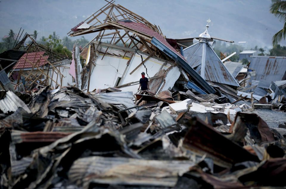 A villager looks for belongings at the earthquake damaged neighborhood of Balaroa in Palu, Central Sulawesi, Indonesia Sunday, Oct. 7, 2018. Christians dressed in their tidiest clothes flocked to Sunday sermons in the earthquake and tsunami damaged Indonesian city of Palu, seeking answers as the death toll from the twin disasters breached 1,700 and officials said they feared more than 5,000 others could be missing. (AP Photo/Aaron Favila)