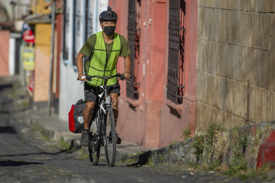 Bonifaz Diaz rides through the streets of Quetzaltenango, Guatemala, Saturday, Jan. 30, 2021. Diaz has pedaled thousands of miles to carry books that people can barter for bags of a cereal mix aimed at providing relief to families suffering chronic malnutrition. (Henning Sac via AP)