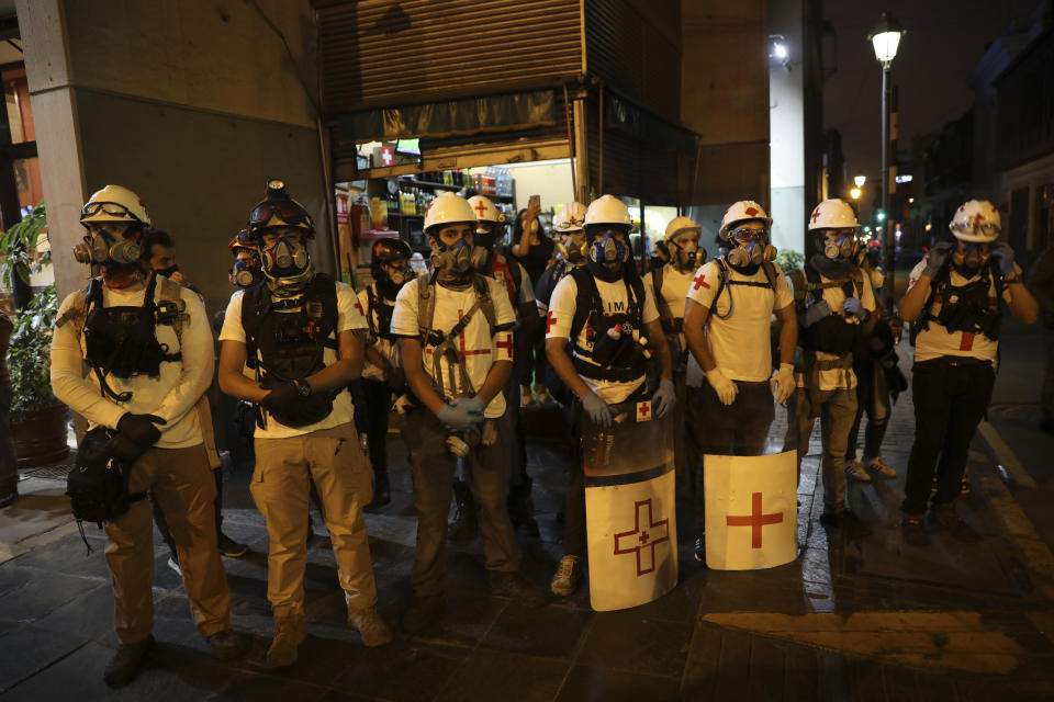 Volunteer medics stand on the sidelines of a protest by people against impunity and for a constitutional reform, after Francisco Sagasti was sworn-in as the new, interim president in Lima, Peru, Tuesday, Nov. 17, 2020. Sagasti's appointment marks a tumultuous week in which thousands took to the streets outraged by Congress' decision to oust popular ex-President Martín Vizcarra. (AP Photo/Rodrigo Abd)