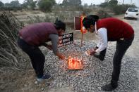 Students light candles next to placards near the spot where a 23-year-old rape victim was set on fire by a gang of men, which included her alleged rapists, in Unnao