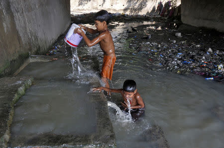 Boys bathe at concrete water pens to cool off under a flyover in a slum area on a hot summer day in Kolkata, India, April 27, 2016. REUTERS/Rupak De Chowdhuri