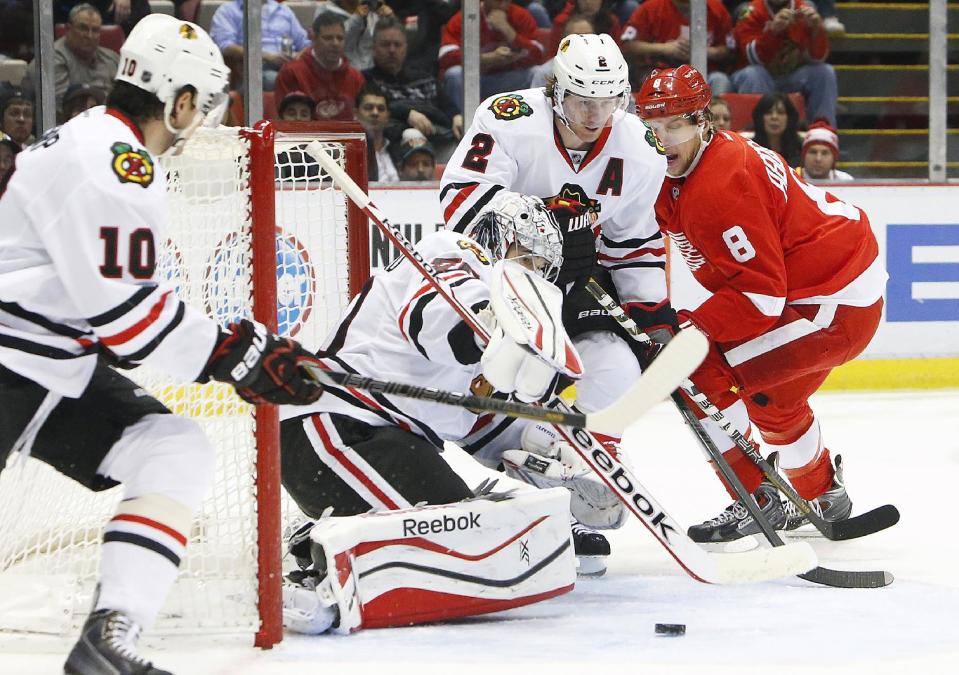 Chicago Blackhawks goalie Corey Crawford, second from left, stops a Detroit Red Wings left wing Justin Abdelkader's (8) shot in the second period of an NHL hockey game Wednesday, Jan. 22, 2014, in Detroit. (AP Photo/Paul Sancya)