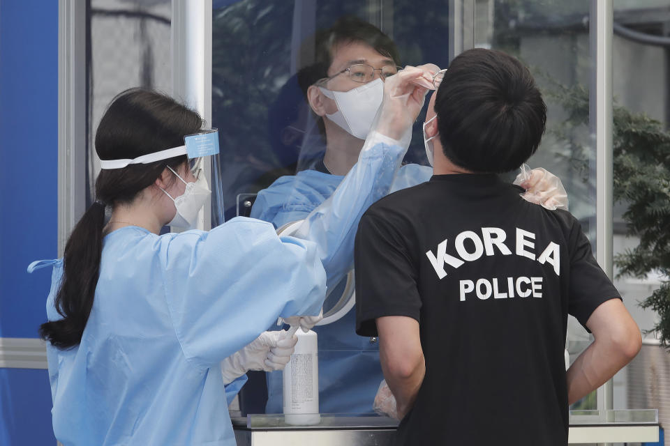 A medical worker takes samples from a police officer during COVID-19 testing at the Seoul Metropolitan Police Agency in Seoul, South Korea, Wednesday, Aug. 19, 2020. (AP Photo/Ahn Young-joon)