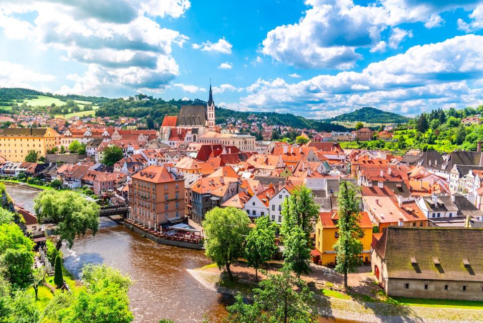 The town of Český Krumlov by a river and surrounded by trees and hills.