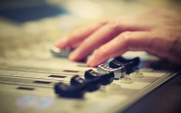 A DJ adjusts controls on a mixer.