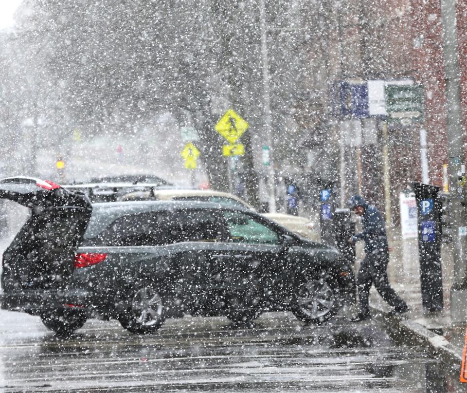 A man returns to his car as he carries packages into the UPS store on Central Avenue in Dover as snow comes down Friday, April 16, 2021.