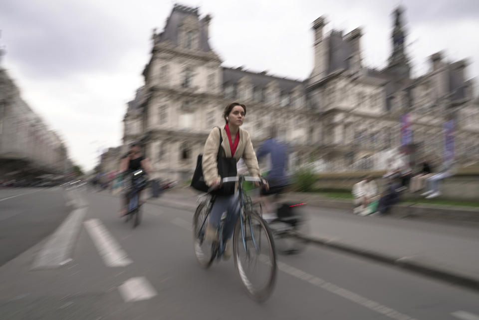 A woman rides past Paris city hall, in Paris, Wednesday, Sept. 13, 2023. Years of efforts to turn car-congested Paris into a more bike-friendly city are paying off ahead of the 2024 Olympics, with increasing numbers of people using the French capital's growing network of cycle lanes. (AP Photo/John Leicester)