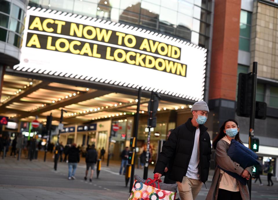 People wearing face masks walk through the shopping area in the city centre of Manchester, north west England on October 8, 2020. - Pubs and restaurants in coronavirus hotspots look set to face fresh restrictions after Downing Street said new data suggests there is "significant" transmission taking place in hospitality settings. A "range of measures" is being looked at, with a particular focus on northern England, where it says infection rates are rising fastest. (Photo by Oli SCARFF / AFP) (Photo by OLI SCARFF/AFP via Getty Images)