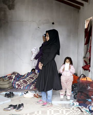 Afghan refugee women and their children stand in an old abandoned beach house as they wait to board a dinghy sailing off for the Greek island of Chios, while they try to travel from the western Turkish coastal town of Cesme, in Izmir province, Turkey, March 6, 2016. REUTERS/Umit Bektas