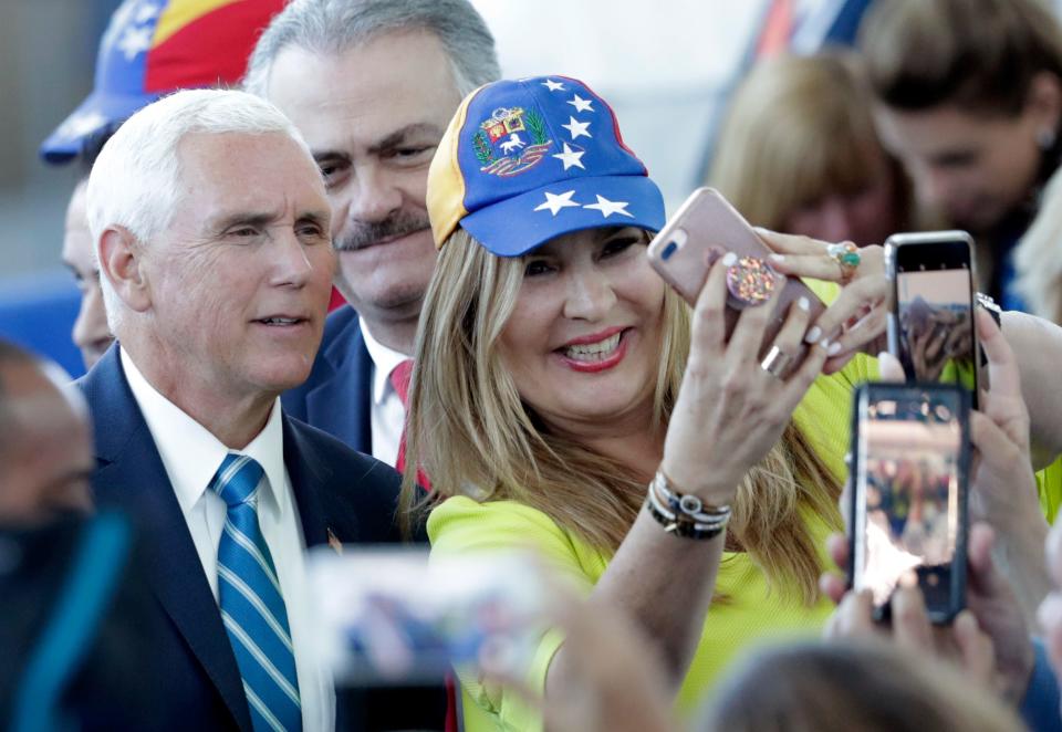 Vice President Mike Pence poses with Paula Tenreiro, who is wearing a cap with the design of the Venezuelan flag, following a tour on the USNS Comfort, Tuesday, June 18, 2019, in Miami.