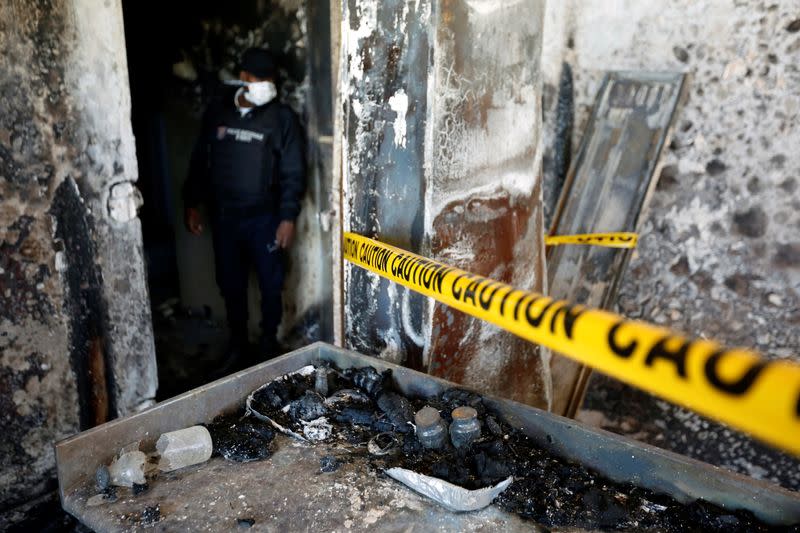 A police officer looks at burnt debris at an orphanage after it was partially destroyed in a fire, in Port-au-Prince