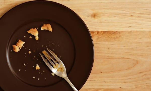 Holiday background image of all that remains of a delicious piece of pumpkin pie.  Plate with crumbs and used fork on wood backg