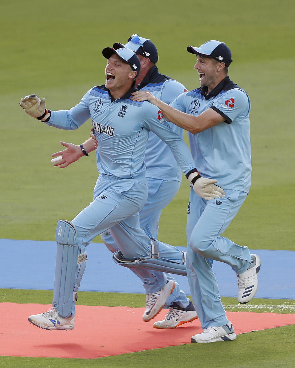 England's Jos Buttler, left, celebrates after running out New Zealand's Martin Guptill to win the Cricket World Cup final match between England and New Zealand at Lord's cricket ground in London, Sunday, July 14, 2019. England won after a super over after the scores ended tied after 50 overs each. (AP Photo/Alastair Grant)