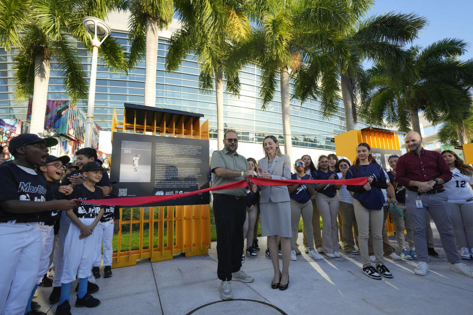 Caroline O'Conner, center right, Miami Marlins president of business operations, and Dennis Rivera Pichardo, exhibit curator and director of photography at Puerto Rican newspaper El Nuevo Dia, cut the ribbon to open a traveling exhibit of images from Roberto Clemente's Major League Baseball career, titled "3000" in a nod to his 3000 career hits, at Miami Marlins' loanDepot Park in Miami, Wednesday, Jan. 31, 2024. The tribute to the late Pittsburgh Pirates outfielder will be on display at the park during baseball's Caribbean Series, which runs from Feb. 1 through Feb. 9. (AP Photo/Rebecca Blackwell)