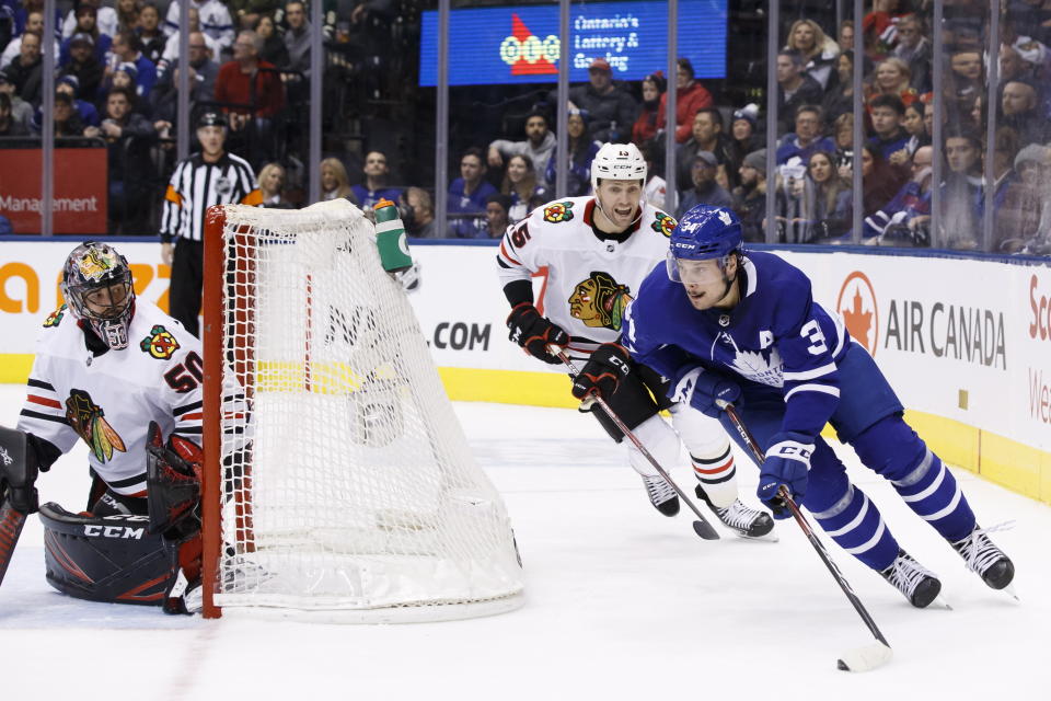 Toronto Maple Leafs centre Auston Matthews (34) works the puck around the net as Chicago Blackhawks goaltender Corey Crawford (50) and centre Zack Smith (15) look on during second period NHL hockey action in Toronto, Saturday, Jan. 18, 2020. (Cole Burston/The Canadian Press via AP)