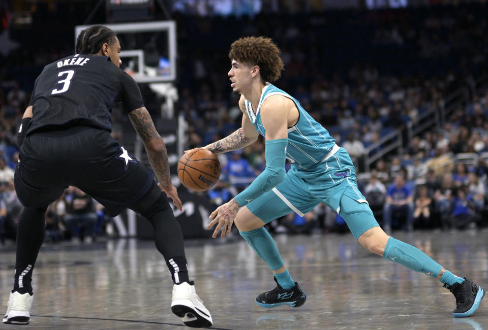 Charlotte Hornets guard LaMelo Ball, right, drives to the basket as Orlando Magic forward Chuma Okeke (3) defends during the first half of an NBA basketball game, Monday, Nov. 14, 2022, in Orlando, Fla. (AP Photo/Phelan M. Ebenhack)