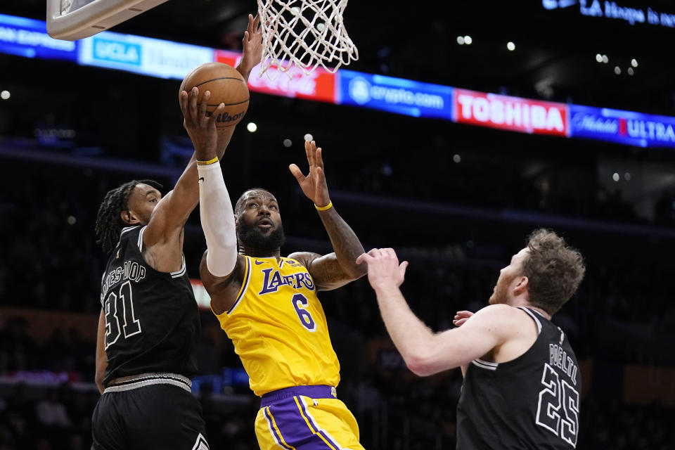 Los Angeles Lakers forward LeBron James, center, shoots as San Antonio Spurs forward Keita Bates-Diop, left, and center Jakob Poeltl defend during the first half of an NBA basketball game Wednesday, Jan. 25, 2023, in Los Angeles. (AP Photo/Mark J. Terrill)