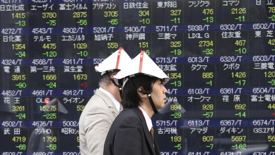 Office workers wearing collapsible helmets walk by an electronic stock board of a securities firm during their disaster drill in Tokyo Thursday, Feb. 13, 2014. Asian stocks were mostly lower Thursday, led by a fall in Tokyo after Wall Street ended lower for the first time this week. Japan's Nikkei 225, the region's main index, dropped 265.32 points, or 1.79 percent to 14,534.74. (AP Photo/Koji Sasahara)