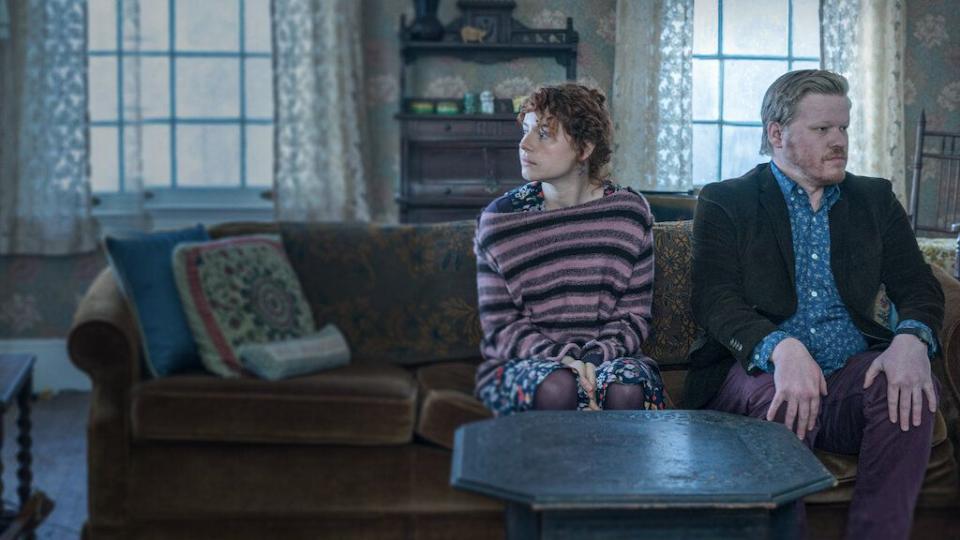 a couple sits together on a couch, looking uncomfortable, in a scene from i'm thinking of ending things, a good housekeeping pick for best sad movies on netflix