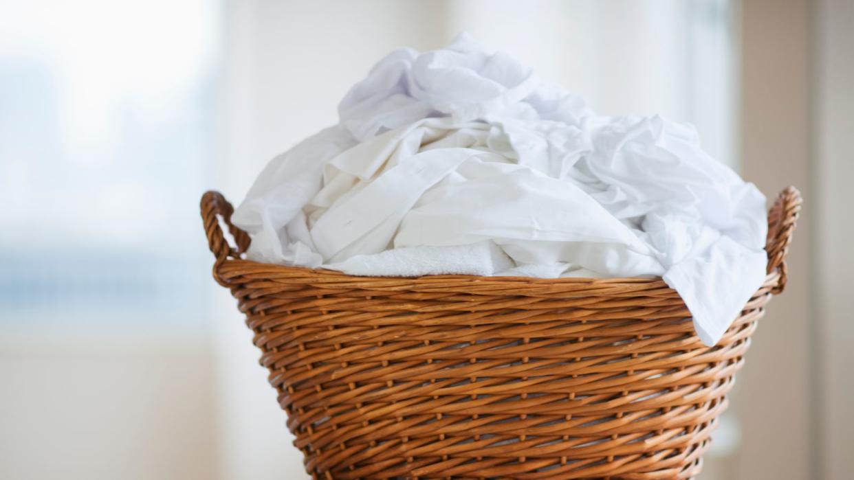  A wicker landry basket with white washing piled up inside 