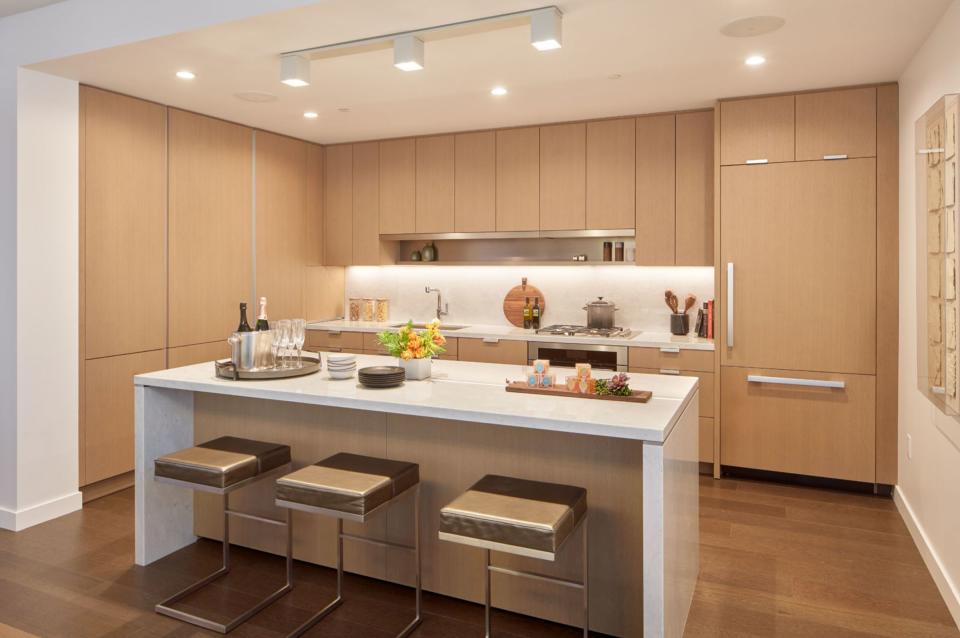 A typical kitchen in a condo unit at The Avery features textured wood paneling, marble counters, and Miele appliances. 