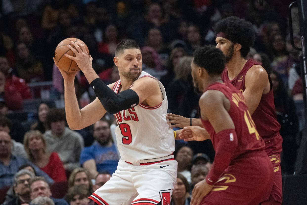 Chicago Bulls' Nikola Vucevic (9) keeps the ball from Cleveland Cavaliers' Donovan Mitchell, right front, and Jarrett Allen during the first half of an NBA basketball game in Cleveland, Wednesday, Feb. 14, 2024. (AP Photo/Phil Long)
