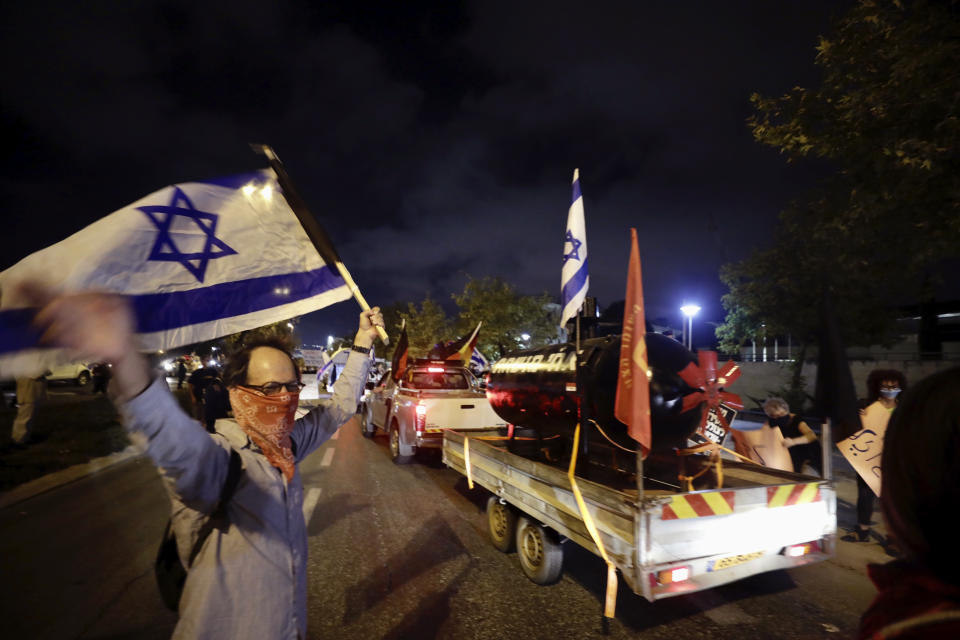 Israeli protesters chant slogans during a demonstration against Israeli Prime Minister Benjamin Netanyahu In Jerusalem, Wednesday, Oct. 14, 2020. Netanyahu was questioned, but not named as a suspect, in a probe related to a possible conflict of interest involving a $2 billion purchase of German submarines that implicated some of his closest associates. Lockdown restrictions that had forced protesters to remain close to their homes in recent weeks were lifted Wednesday, allowing the anti-Netanyahu parade to take place. (AP Photo/Sebastian Scheiner)